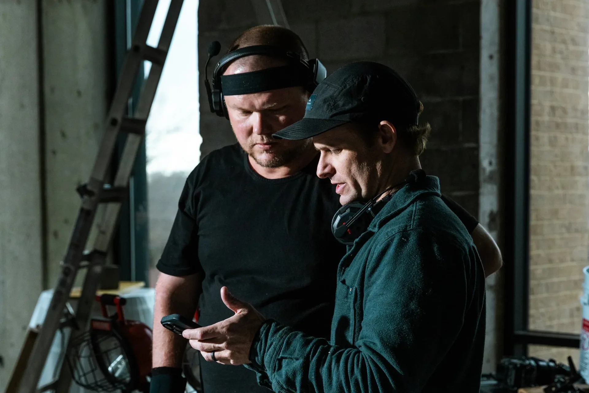 Two crew members on headsets check a shot on a phone between setups