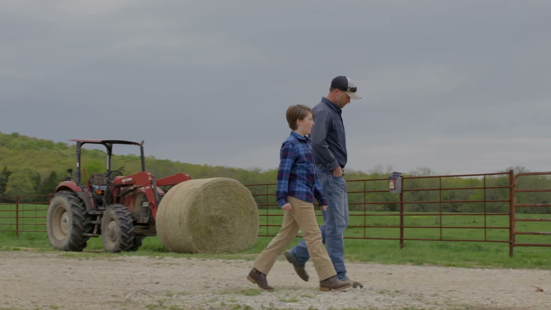 Lincoln Hough and a boy walking past a tractor and a hay bale