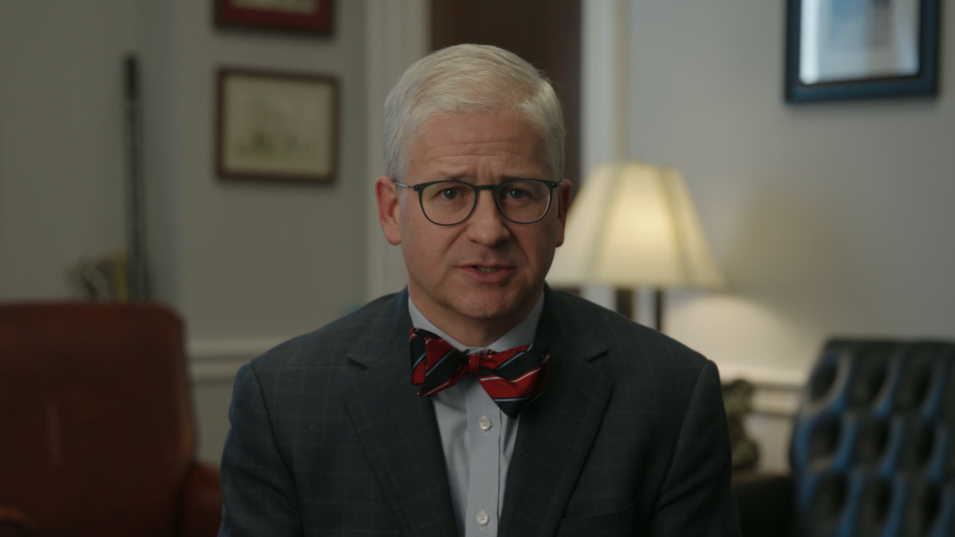 Patrick McHenry in a medium shot with a practical lamp glowing behind him
