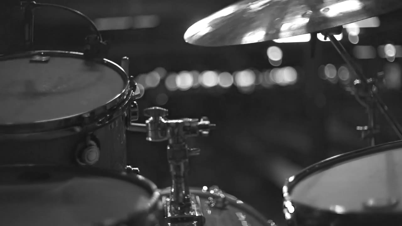 Cymbals and drum kit lit from behind on a darkened stage