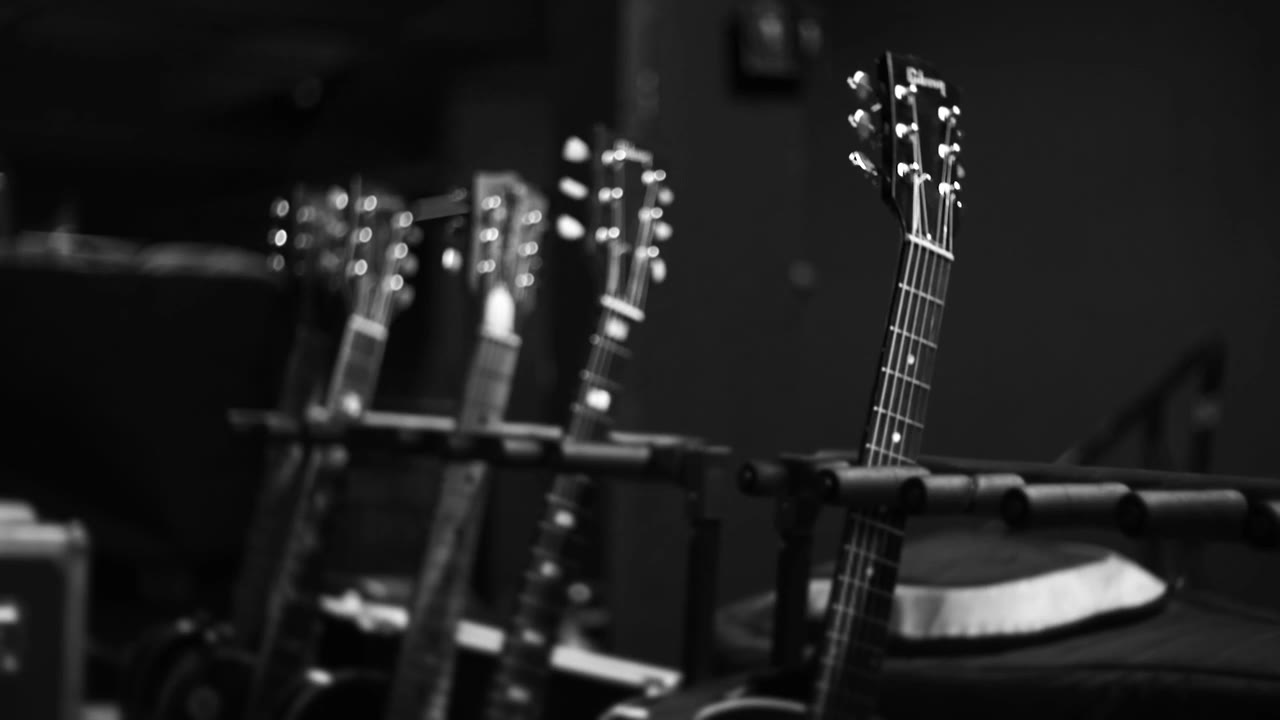 Acoustic guitars racked on stands in the wings before the set