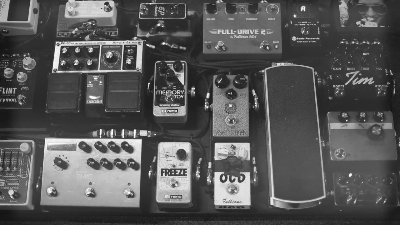 Overhead view of a guitar pedalboard laid out on the stage floor