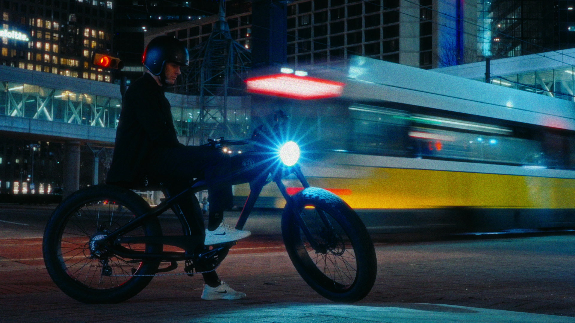Bike rider leaning through a parking ramp curve with headlight flare and concrete lines.