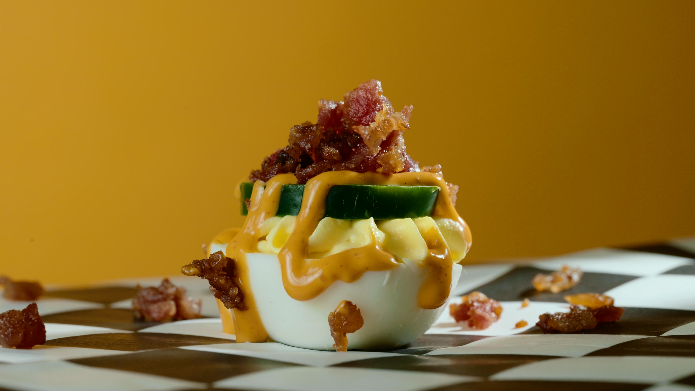 Close tabletop hero frame of bacon mustard deviled eggs with warm garnish detail.