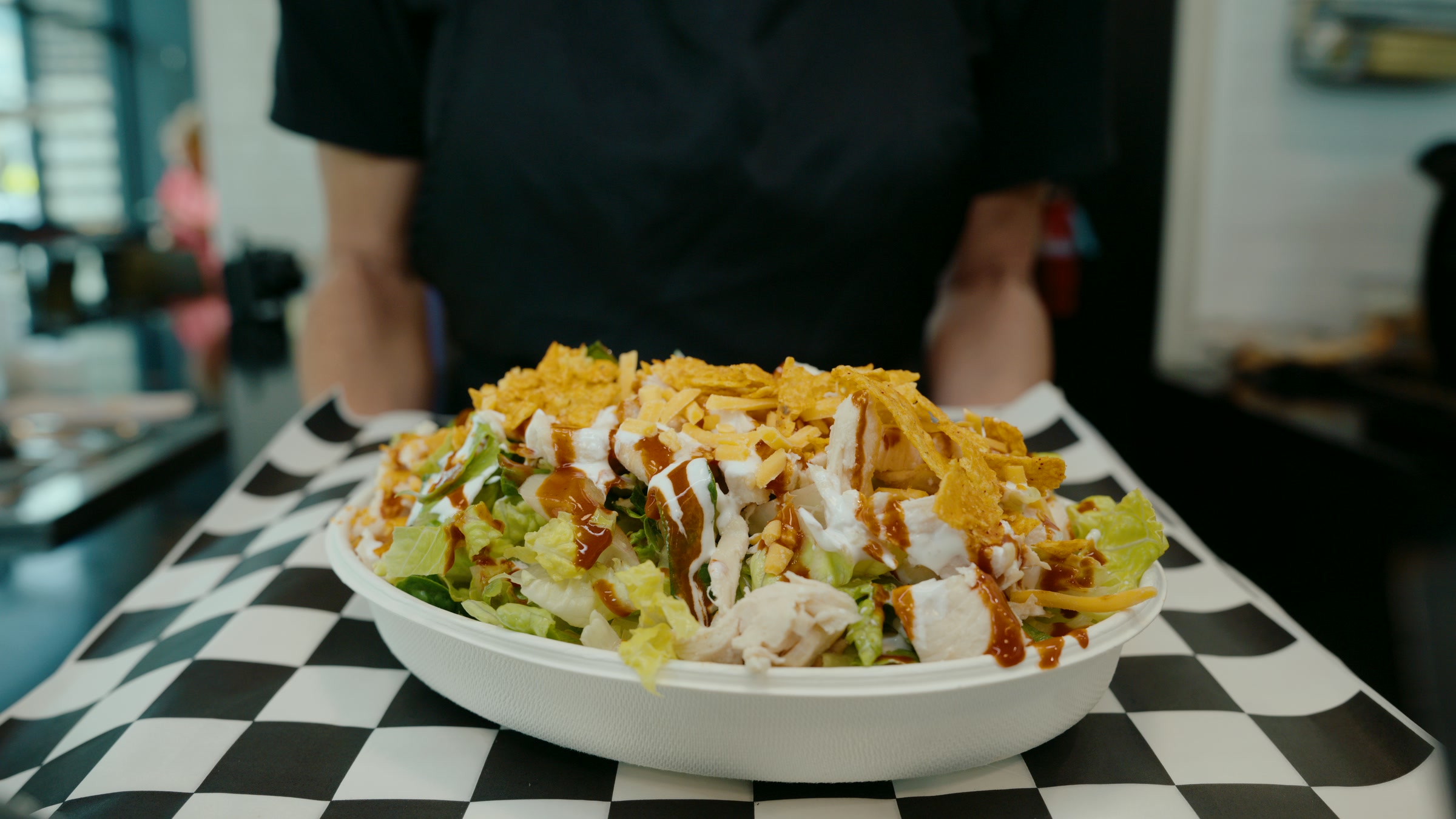 Loaded salad bowl served at table with layered toppings and bright garnish.