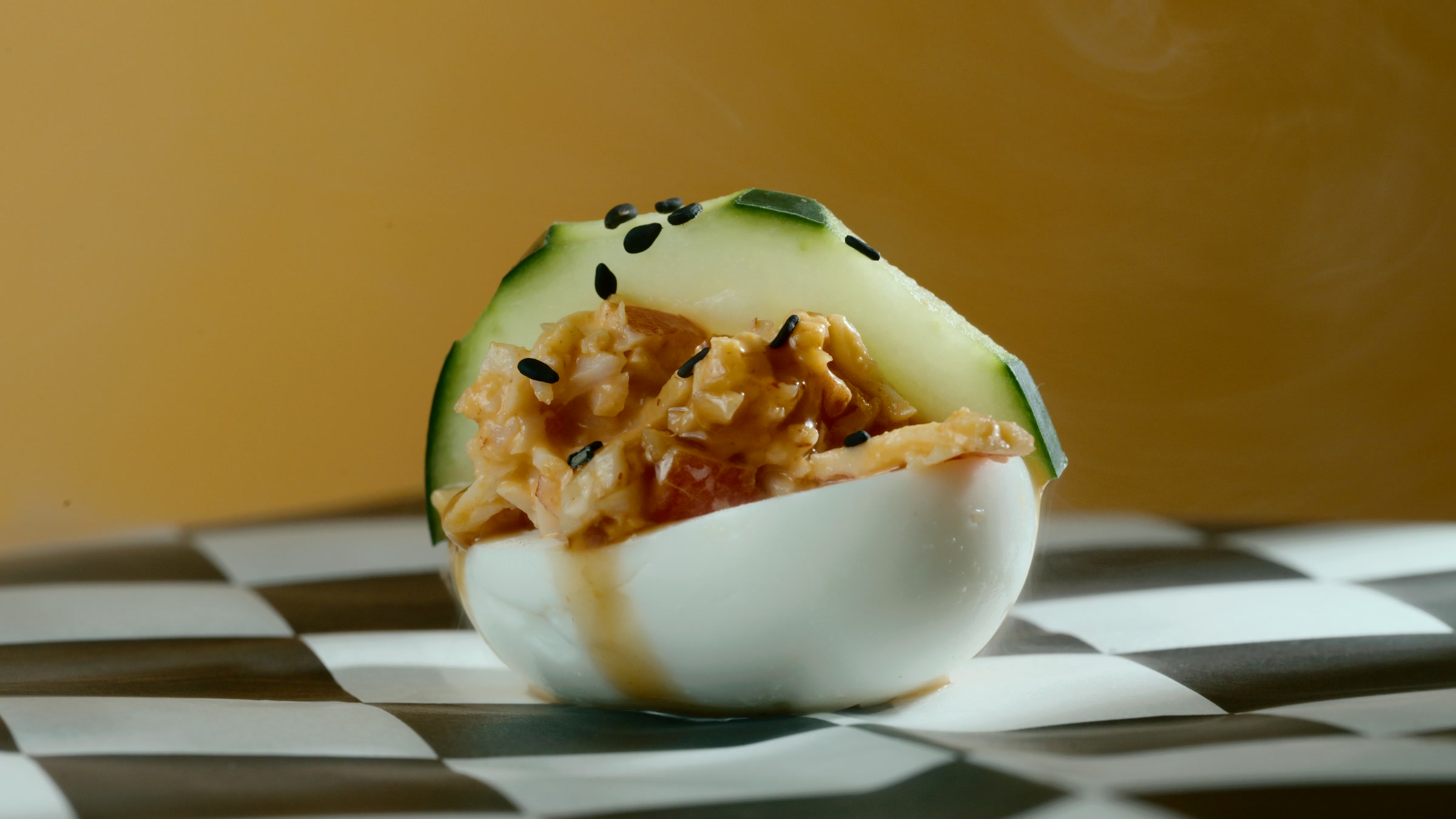 Profile food frame with sesame cucumber garnish stacked over a deviled egg.
