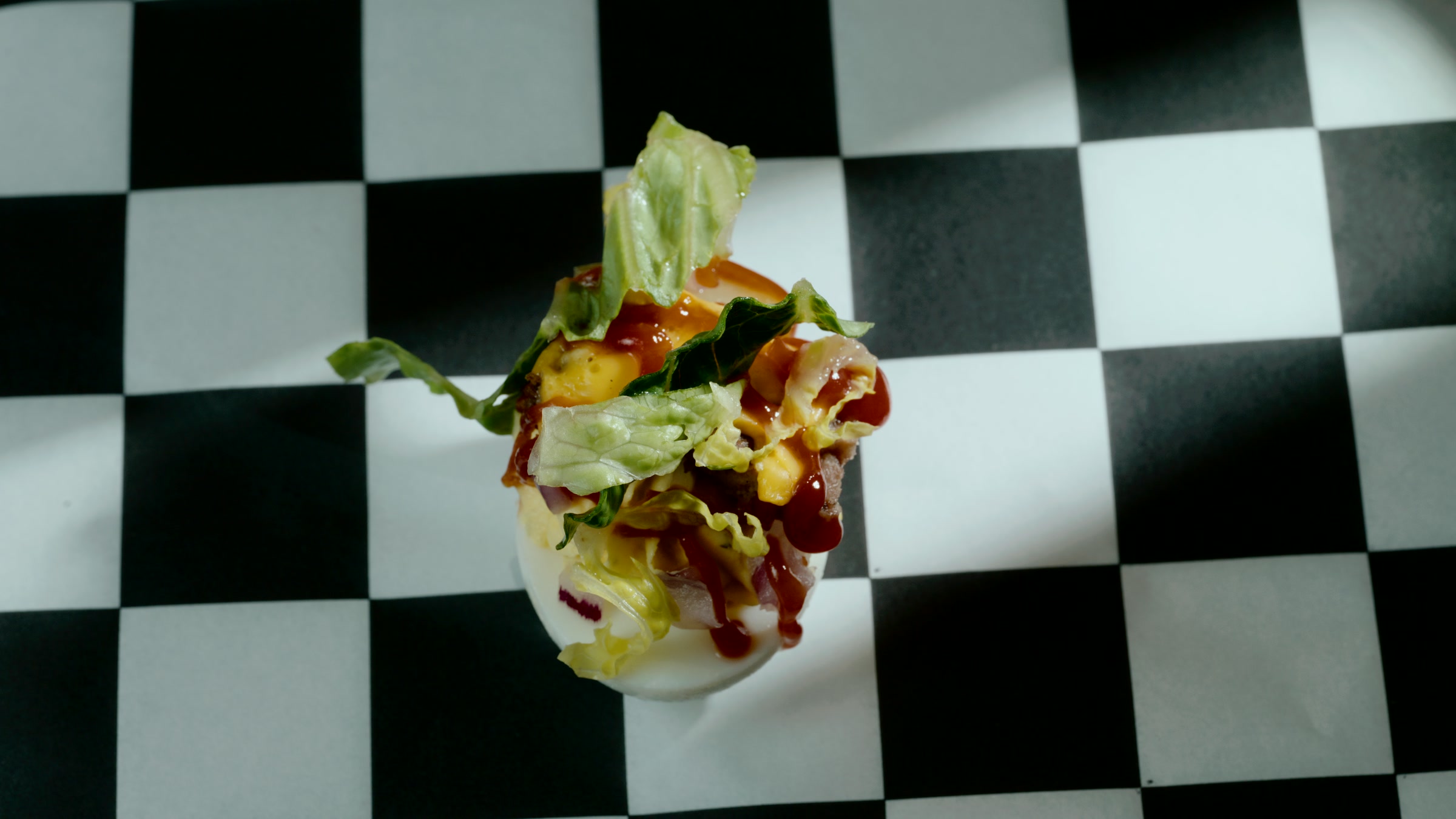 Top down deviled egg layout on a checkerboard surface with graphic table styling.