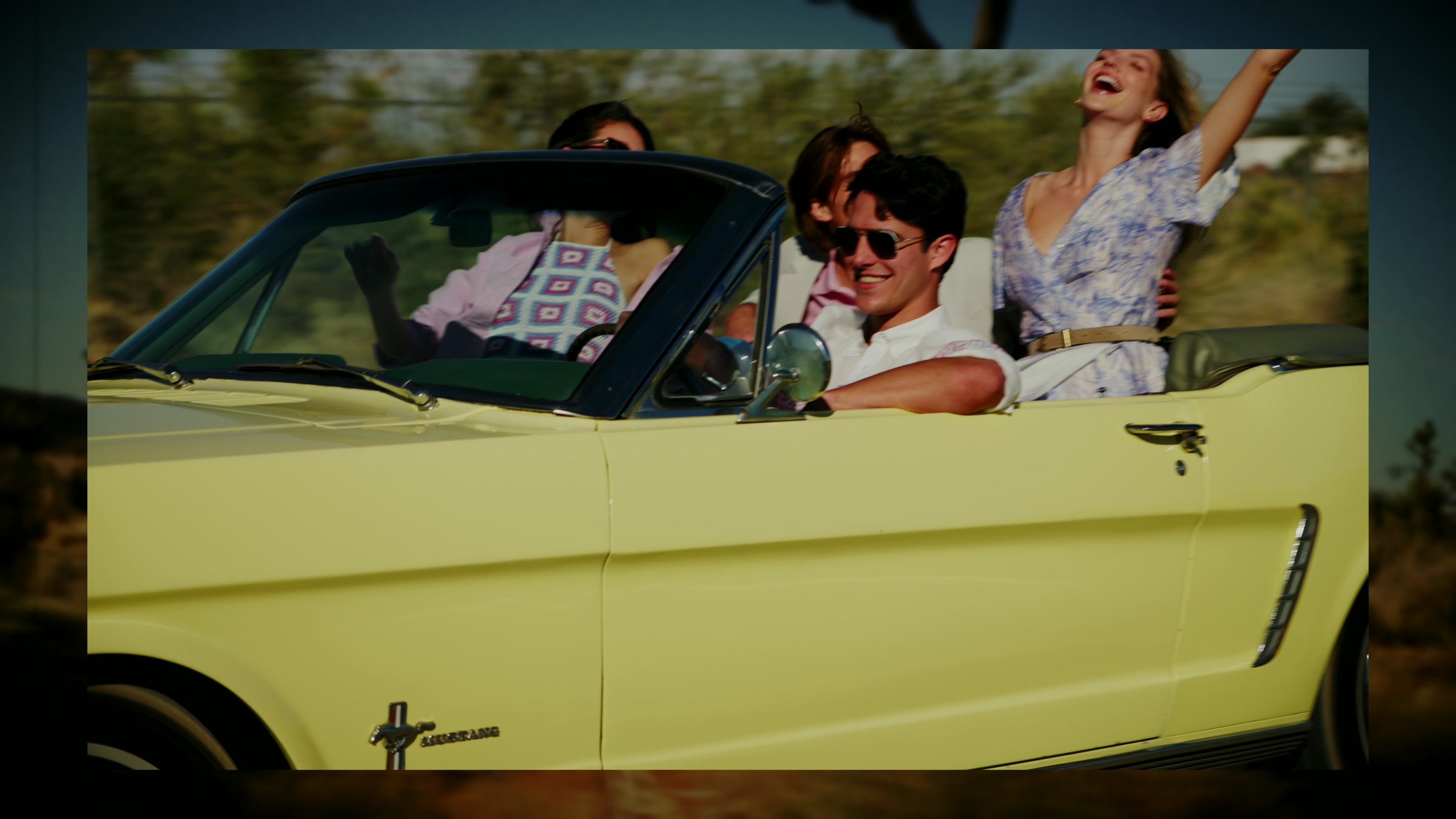 Close lifestyle passenger moment inside a moving convertible with sunlit desert road energy.
