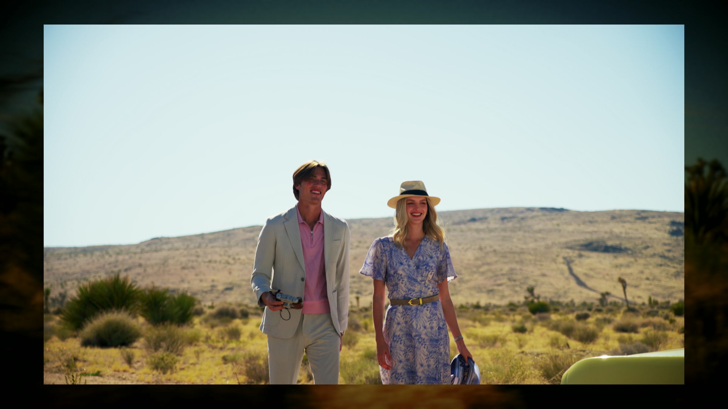 Styled couple arriving in a desert location beside the yellow convertible.