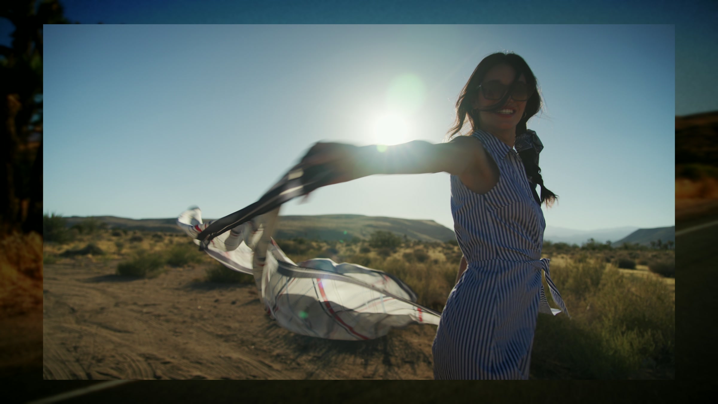 Fashion subject in desert motion with scarf movement, bright sand, and open sky.