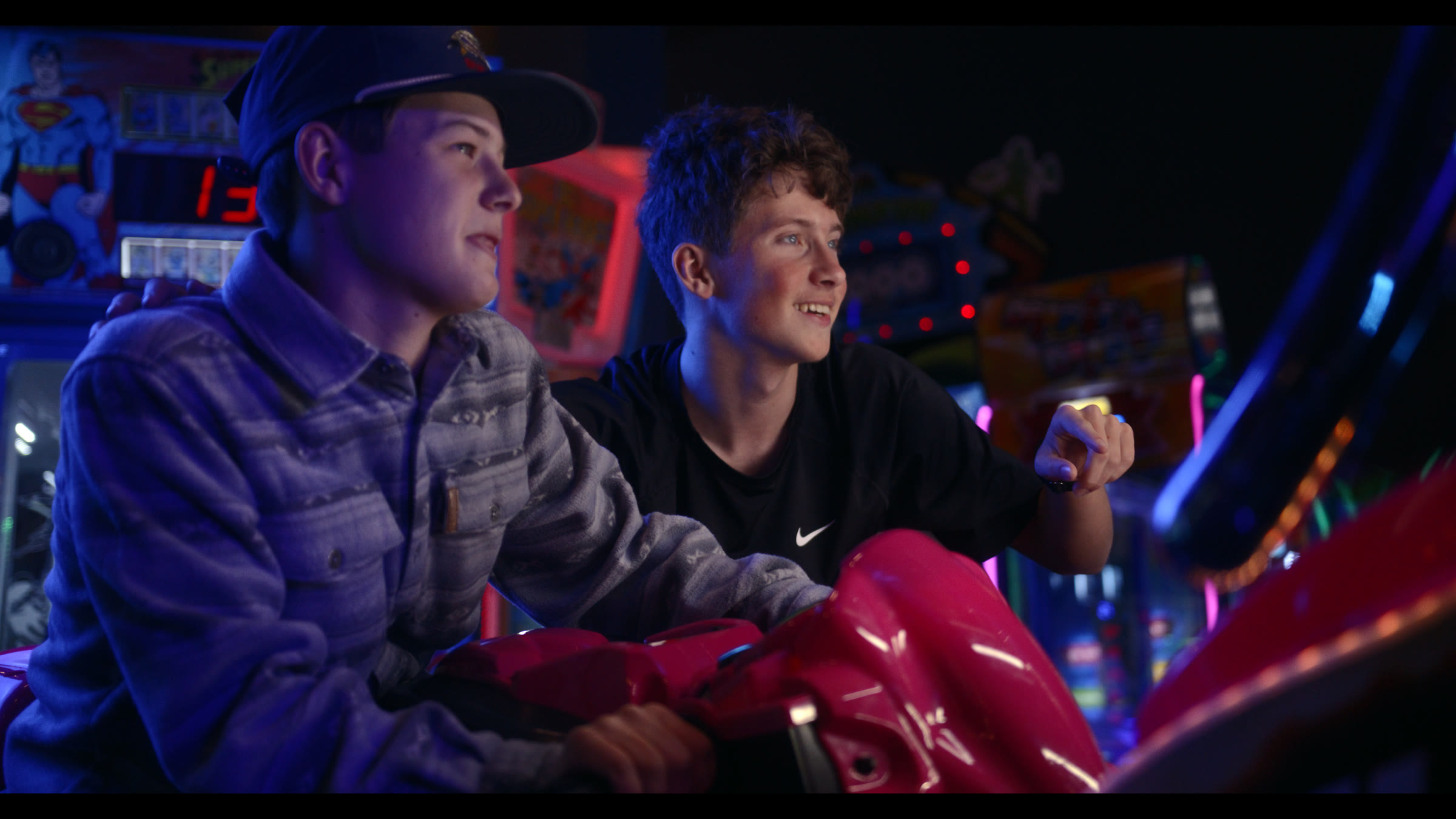 Arcade ride frame with two kids in colorful practical light and active foreground motion.