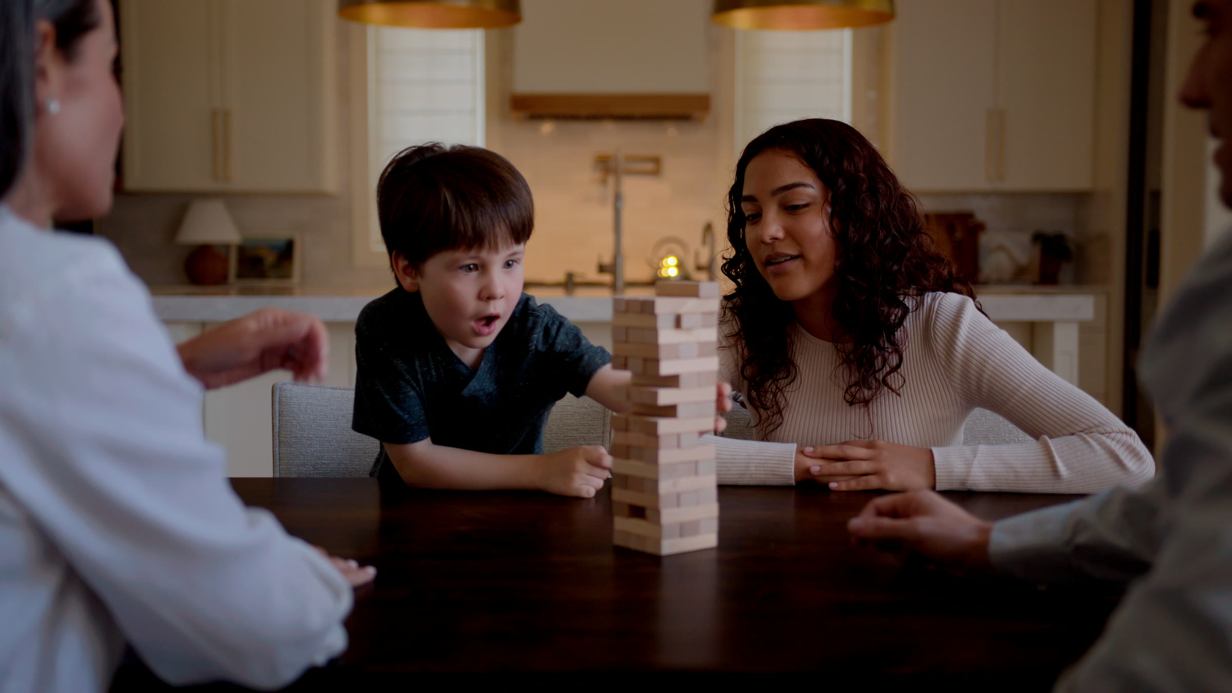Wide family game table frame with Jenga tower centered under warm pendant light.