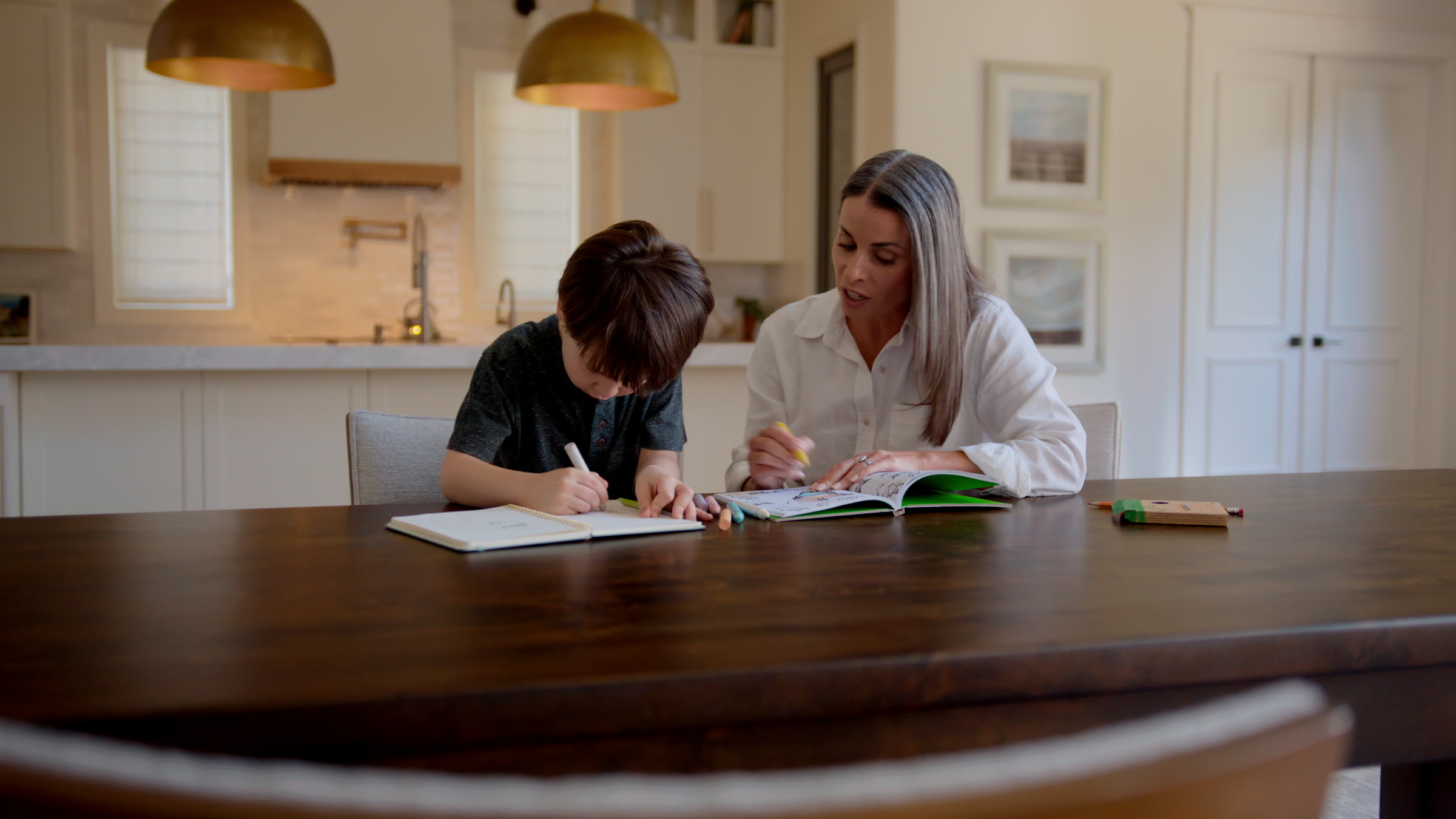 Study table frame with workbook, warm pendant light, and quiet family focus.