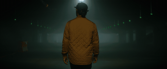 Looping anamorphic fog walk with green tunnel lights and centered silhouette movement.