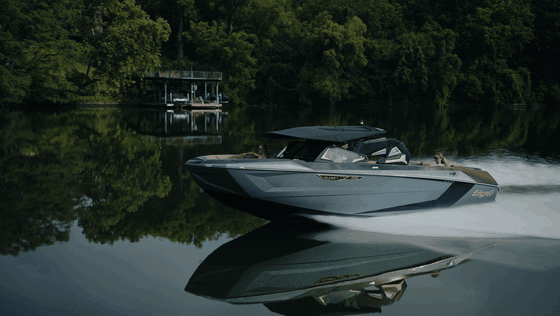 Looping side profile of a Tige boat moving across mirror-still lake water and a dark green reflection.