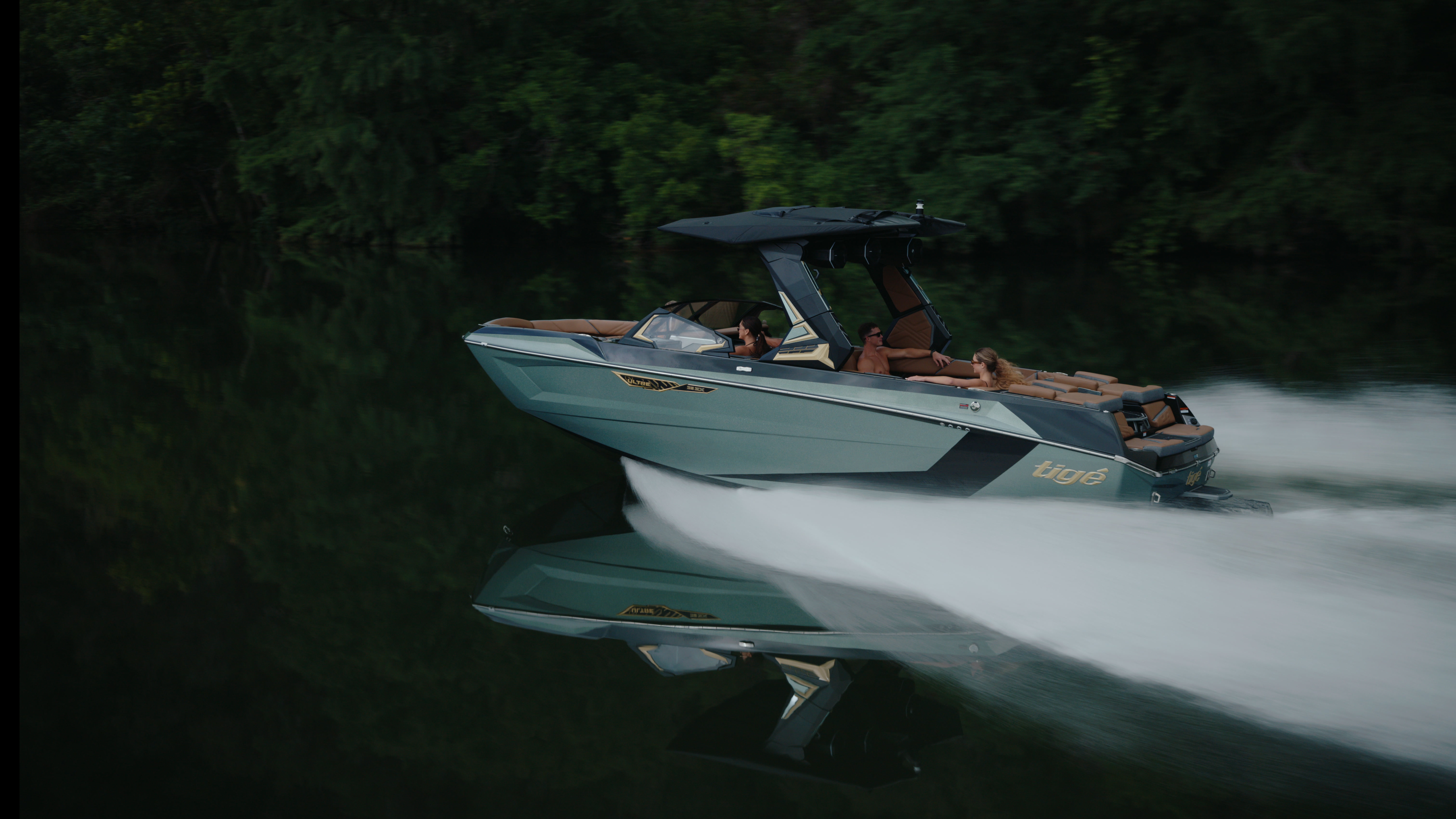 Low-light Tige boat profile cutting across a dark forest reflection with bright wake detail.