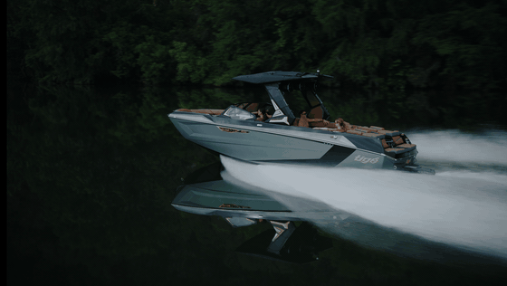 Looping low-light Tige boat profile crossing a dark forest reflection with a bright wake.